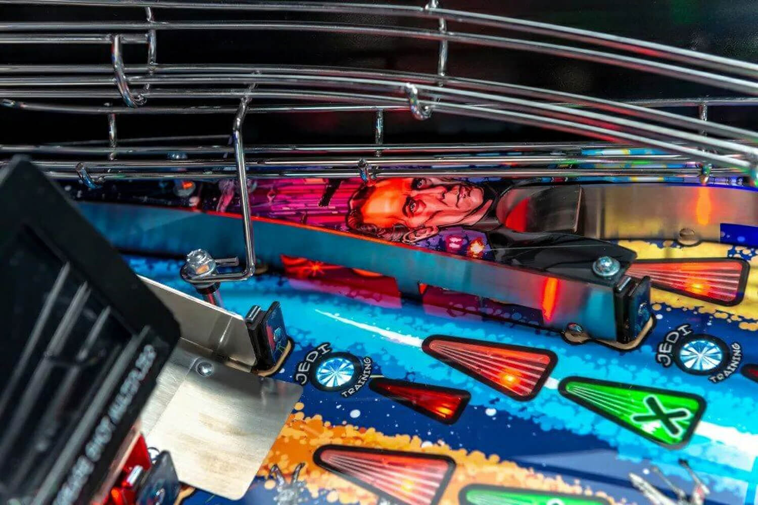 Close-up of a pinball machine with colourful playfield and player figure.