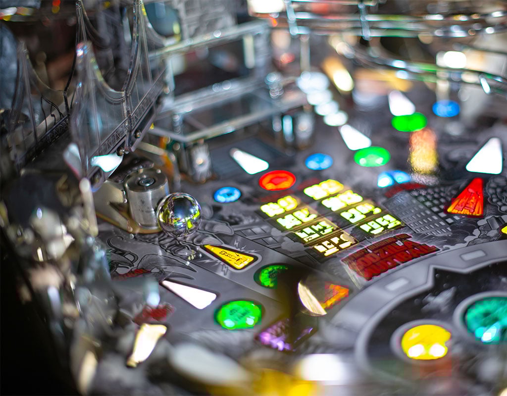 Close-up of a pinball machine with colorful lights and buttons