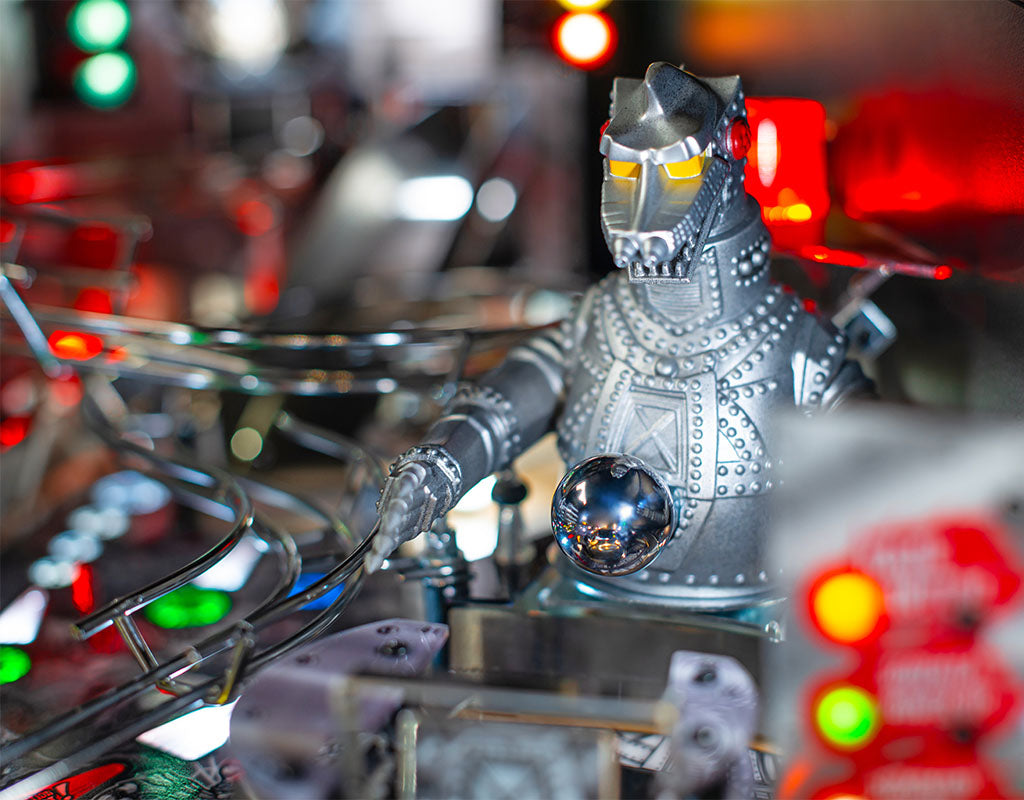 Metallic robot figurine on a pinball machine with colorful lights in the background
