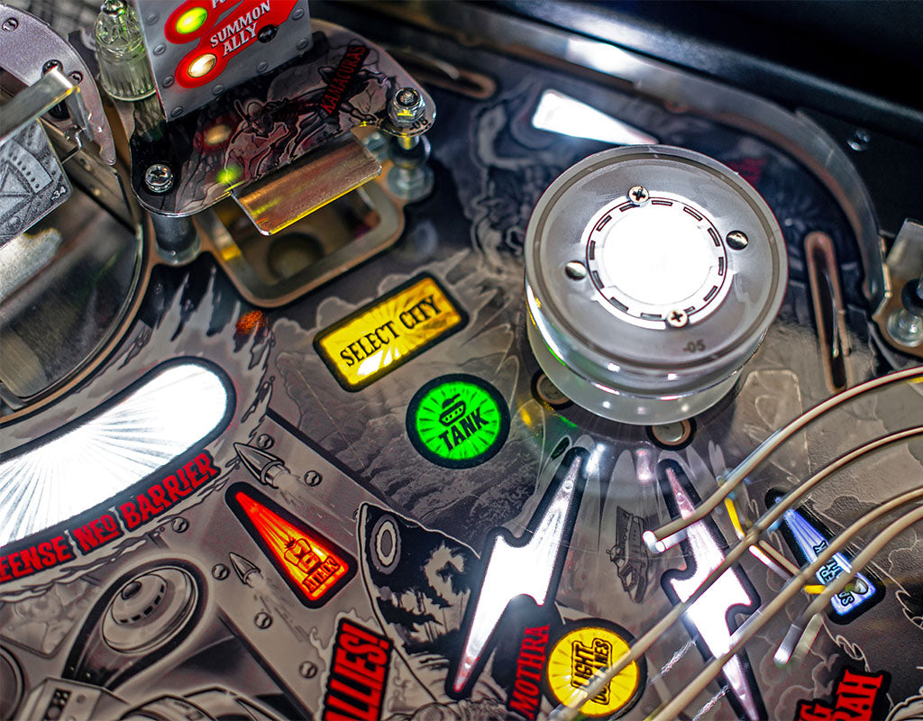 Close-up of a pinball machine with various playfield elements and buttons.