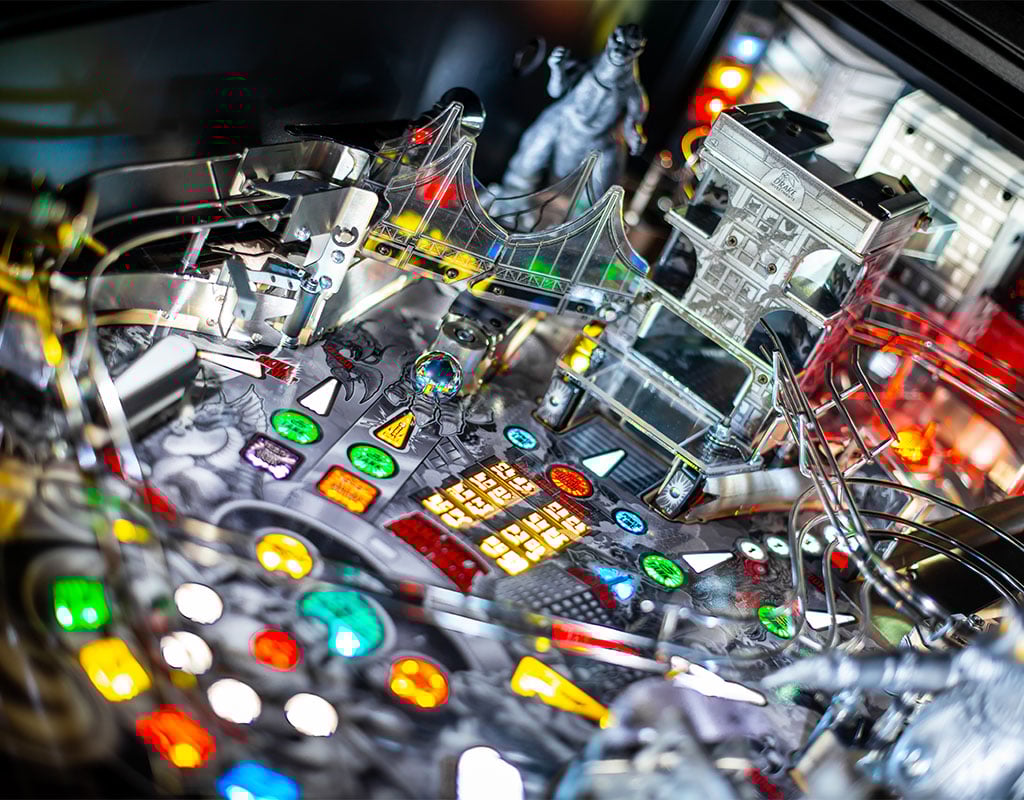 Close-up of a pinball machine with colorful lights and mechanical components.