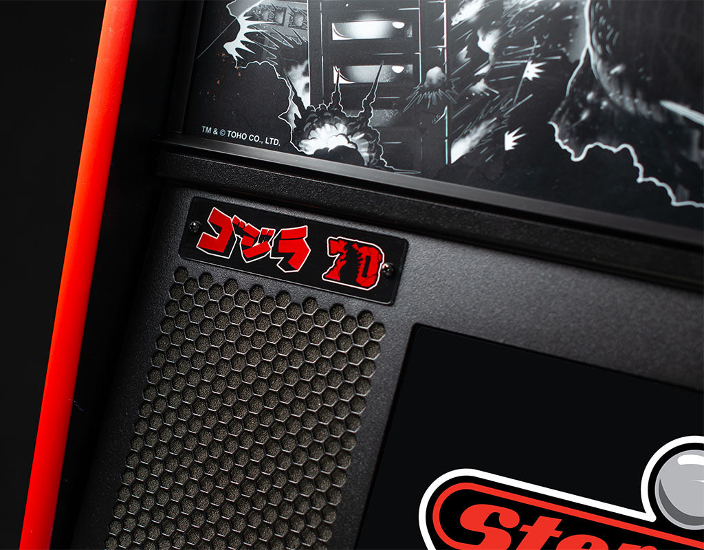 Close-up of a vintage arcade machine with 'Godzilla' branding and black and white graphics.